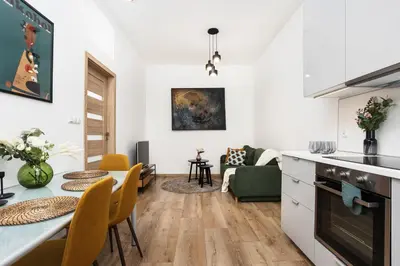 a kitchen and living room with a table and chairs at Apartment à côté the train station - by Upstairs in Kraków