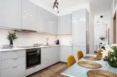 a kitchen with white cabinets and a table with chairs at Apartment à côté the train station - by Upstairs in Kraków