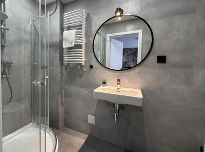 a bathroom with a sink and a mirror and a shower at Garbarska 22 Aparthotel in Kraków