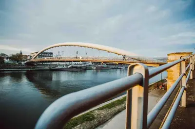 a bridge over a river with boats in the water at HAPPY MOMENTS APARTMENTS in Kraków