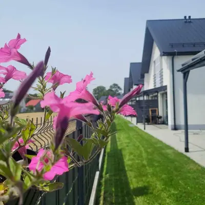 a fence with pink flowers in front of a house at Słoneczne Zacisze Las obok Zatora in Las