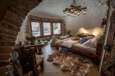 a bedroom with a bed and a table and windows at Domek Hobbita z jaskinią SPA - Osada Jaworzyny in Tokarnia