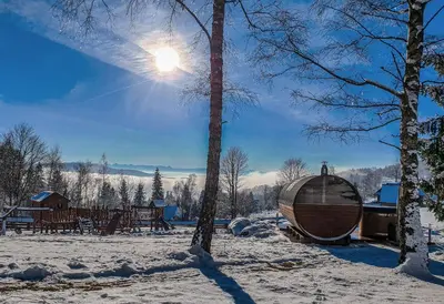 a wooden tub sitting in the snow next to a tree at Domek Hobbita z jaskinią SPA - Osada Jaworzyny in Tokarnia