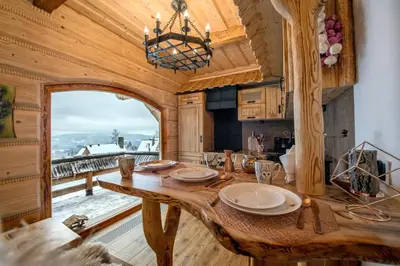 a kitchen with a wooden table and a large window at Baśniowy Domek Kolędówka z jaskinią SPA - Osada Jaworzyny in Tokarnia