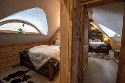a bedroom with a bed in a room with a window at Baśniowy Domek Kolędówka z jaskinią SPA - Osada Jaworzyny in Tokarnia