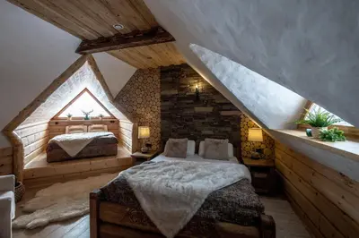 a bedroom with two beds in a attic at Baśniowy Domek Kolędówka z jaskinią SPA - Osada Jaworzyny in Tokarnia