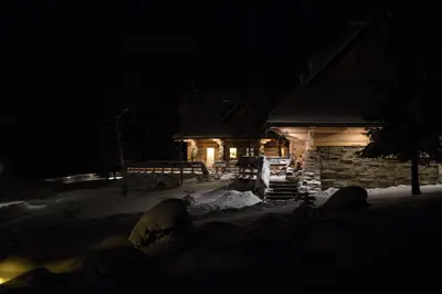 a house at night with snow in front of it at Baśniowy Domek Groń z Jaskinią SPA - Osada Jaworzyny in Tokarnia