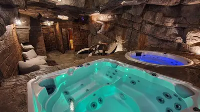 a bathroom with a blue tub in a cave at Baśniowy Domek Groń z Jaskinią SPA - Osada Jaworzyny in Tokarnia