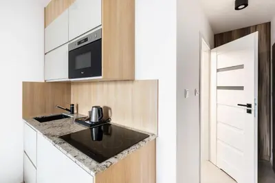a white kitchen with a black table and a black chair at Apartamenty Platinex 6 in Kraków