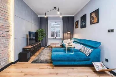 a living room with a blue couch and a brick wall at Zender Kazimierz Apartment in Kraków