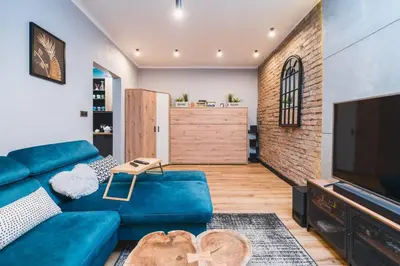 a living room with a blue couch and a television at Zender Kazimierz Apartment in Kraków