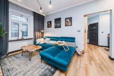 a living room with a blue couch and a table at Zender Kazimierz Apartment in Kraków