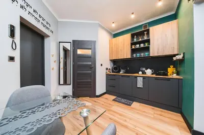 a kitchen with black cabinets and a glass table at Zender Kazimierz Apartment in Kraków