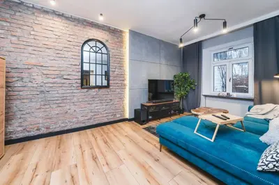 a living room with a blue couch and a brick wall at Zender Kazimierz Apartment in Kraków