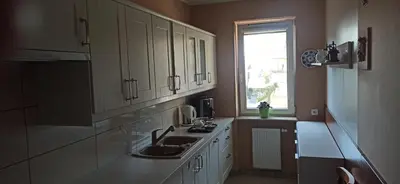 a kitchen with white cabinets and a sink and a window at Apartamenty Kraków -Podgorze M&W in Kraków