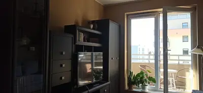 a living room with a book shelf and a window at Apartamenty Kraków -Podgorze M&W in Kraków