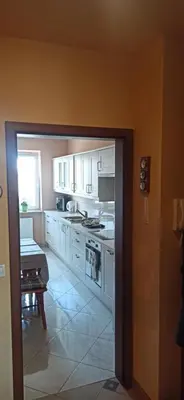 a kitchen with white cabinets and a table at Apartamenty Kraków -Podgorze M&W in Kraków