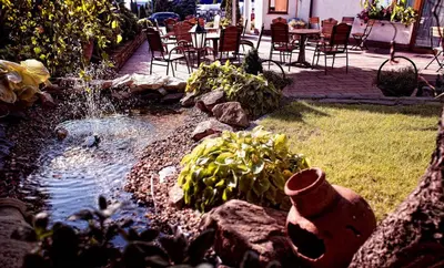a garden with a pond with chairs and a table at Gościniec Na Rozdrożu in Libiąż