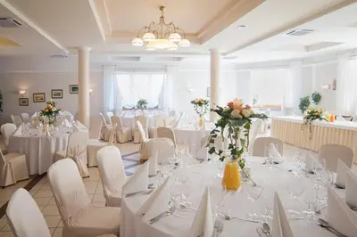 a banquet hall with white tables and white chairs at Gościniec Na Rozdrożu in Libiąż