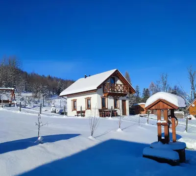 a house with snow on the ground in front of it at Słoneczna Chałupka in Zawoja