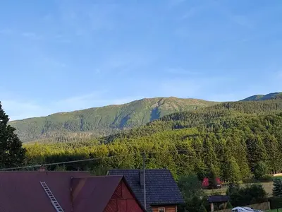 a view of a mountain with a red house and trees at Słoneczna Chałupka in Zawoja