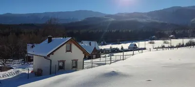 a small house on a hill with mountains in the background at Słoneczna Chałupka in Zawoja
