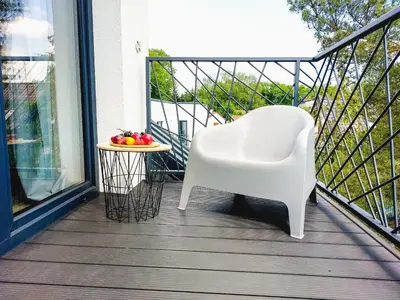 a white chair on a balcony with a bowl of fruit on a table at MR HOME APARTMENTS - Limba in Kraków
