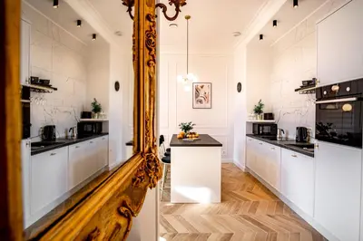 a kitchen with white cabinets and a mirror at Luxury Apartment St. Sebastian in Kraków
