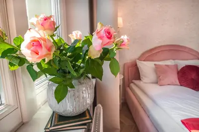 a vase with pink roses on a table in a bedroom at Luxury Apartment St. Sebastian in Kraków