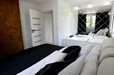 a bedroom with a large bed and a bathroom at Apartamenty Modrzewiowa Zator in Piotrowice