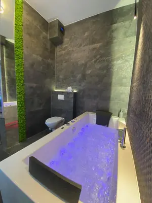 a bathroom with a bath tub with purple water at Apartament biały z jacuzzi in Kraków