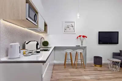 a white kitchen with a counter and stools at Apartament biały z jacuzzi in Kraków
