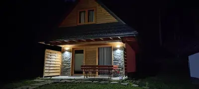 a house with a bench in front of it at night at LEŚNE ZACISZE OCHOTNICA in Ochotnica Górna