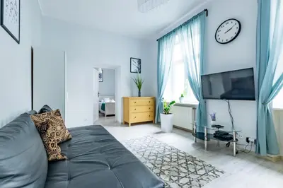 a living room with a couch and a clock on the wall at Wawel Castle Apartment in Kraków