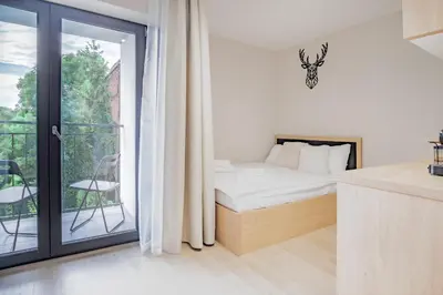 a white bedroom with a bed and a balcony at Iron Apartments by MB Apartments in Kraków