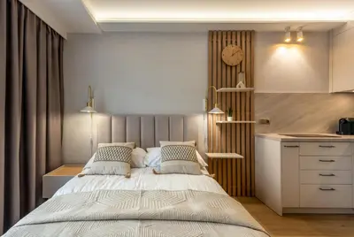 a bedroom with a bed and a clock on the wall at Iron Apartments by MB Apartments in Kraków