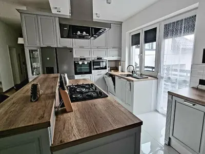 a kitchen with white cabinets and a wooden counter top at Apartamenty ASLux - Noclegi Energylandia Zator in Zator