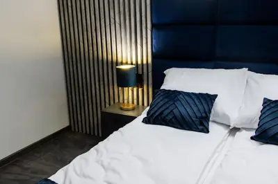 a bed with a blue headboard and two pillows at Apartamenty ASLux - Noclegi Energylandia Zator in Zator