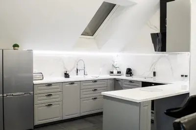 a white kitchen with white counters and a refrigerator at Apartamenty ASLux - Noclegi Energylandia Zator in Zator