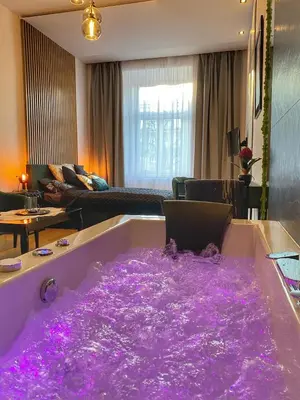 a bath tub covered in purple lights in a living room at Apartament czarny z jacuzzi in Kraków