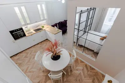 a small white kitchen with a table and a dining room at Olver Apartment in Kraków