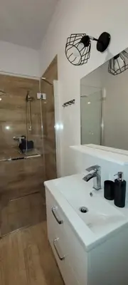 a bathroom with a sink and a shower with a mirror at Nest Apartament in Zator