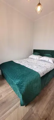 a bedroom with a bed with a green comforter at Nest Apartament in Zator