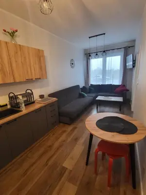 a kitchen and a living room with a table and a couch at Nest Apartament in Zator
