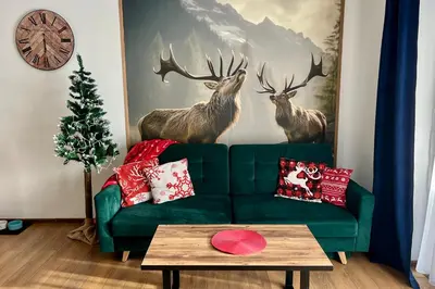 a living room with a green couch and deer mural at Gorczański Resort Domek w Górach Sauna Jacuzzi in Nowy Targ