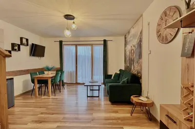 a living room with a green couch and a table at Gorczański Resort Domek w Górach Sauna Jacuzzi in Nowy Targ