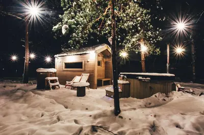 a cabin in the snow at night with lights at La Playa Resort & Camp Trzebinia in Trzebinia