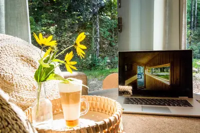 a laptop computer sitting on a table with a drink at La Playa Resort & Camp Trzebinia in Trzebinia