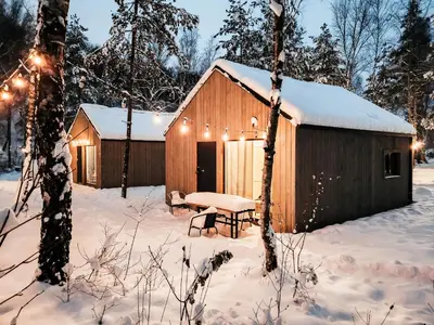 a wooden barn with a picnic table in the snow at La Playa Resort & Camp Trzebinia in Trzebinia