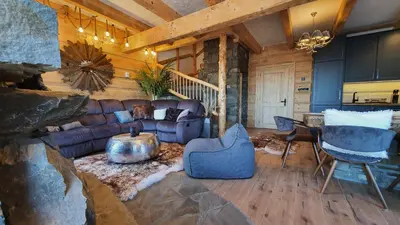 a living room with a couch and a table and chairs at Luksusowy domek z jaskinią SPA - Osada Jaworzyny in Tokarnia
